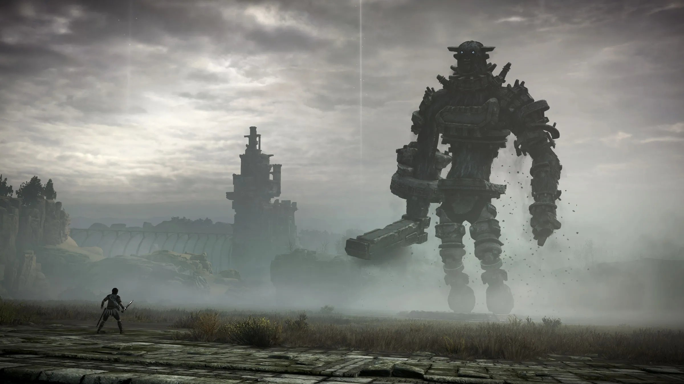 A screenshot from Shadow of the Colossus, showing a very small player character in the foreground and a huge golem rising out of the mists in the background